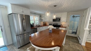 A modern kitchen with stainless steel appliances, a wooden island, and pendant lighting. - Private Falmouth home perfect for family fun - hot tub, fire pit, and game room! (Falmouth)