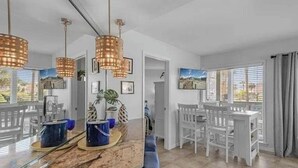 A modern kitchen with a marble countertop, pendant lights, and a dining area with white chairs and a bench. - Sugar Sands-Luxury 1st Floor 2BR 2BA Private Beach (Gulf Shores)