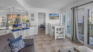 A modern kitchen with a bar area, a dining table with chairs, and a large sliding glass door leading to a balcony. - Sugar Sands-Luxury 1st Floor 2BR 2BA Private Beach (Gulf Shores)