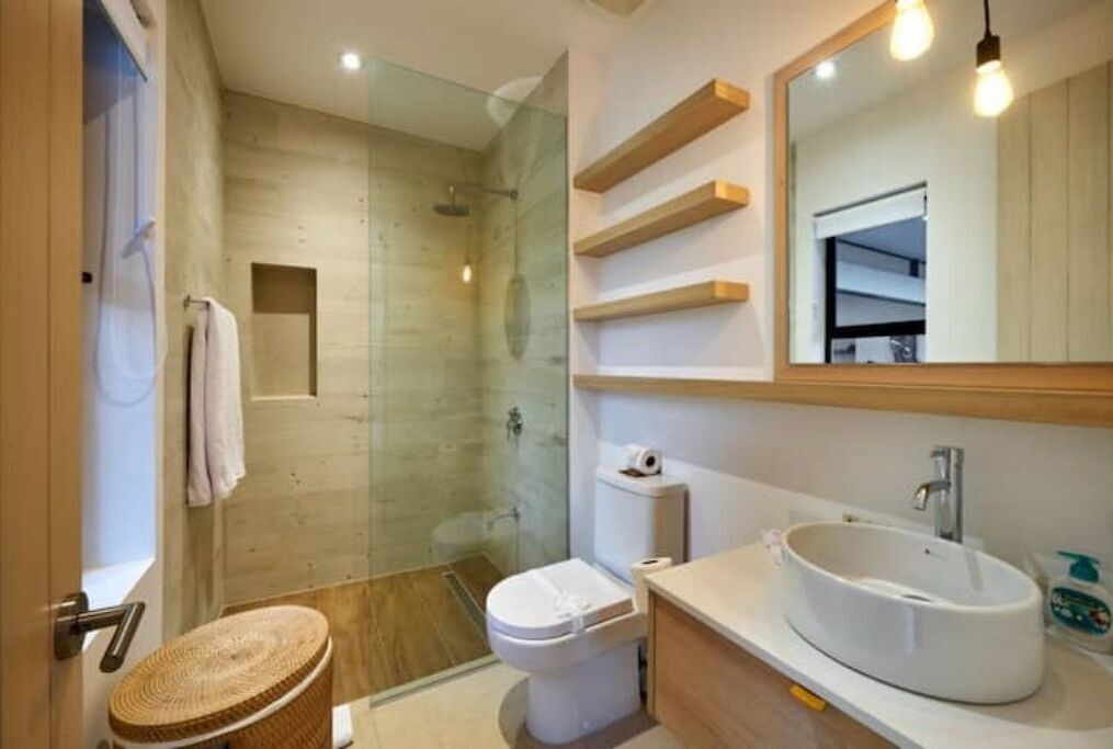 A modern bathroom with a glass-enclosed shower, a white toilet, and a large oval sink.