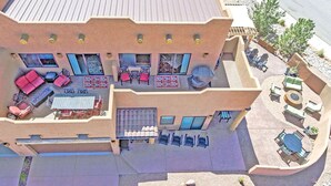 A two-story building with a patio area featuring outdoor seating and a pool. - Gorgeous Moab Retreat with Red Rock and La Sal Mountain Views - South Valley (Moab)