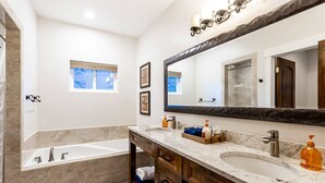 A modern bathroom with a double sink vanity, a large mirror, and a bathtub. - Gorgeous Moab Retreat with Red Rock and La Sal Mountain Views - South Valley (Moab)
