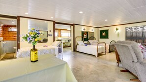Habitación de hotel con cama, sofá, mesa de comedor y una botella de aceite de oliva, y vista al exterior.