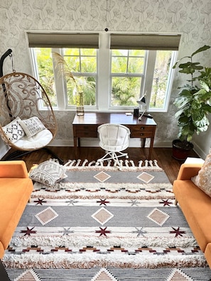 A cozy room with a desk, chair, and two sofas.