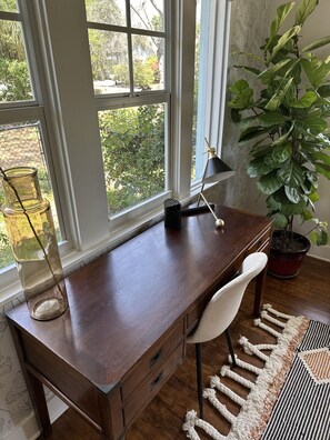 Un bureau en bois, une chaise blanche, une lampe et une plante en pot.
