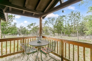 Une terrasse en bois avec une table ronde et deux chaises, entourée d’une balustrade en bois.