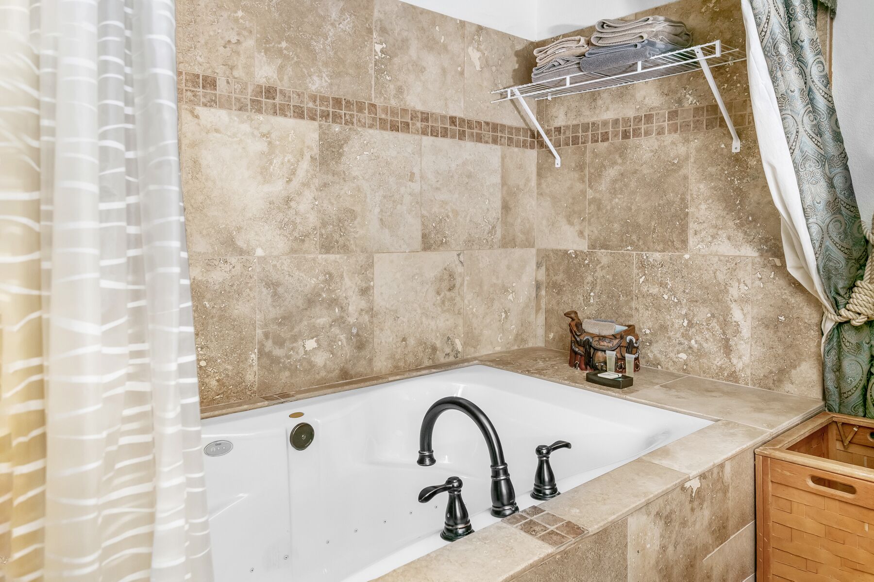 Un baño con bañera, cortina de ducha, toallero y un mueble de madera.
