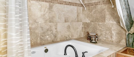 Un baño con bañera, cortina de ducha, toallero y un mueble de madera.