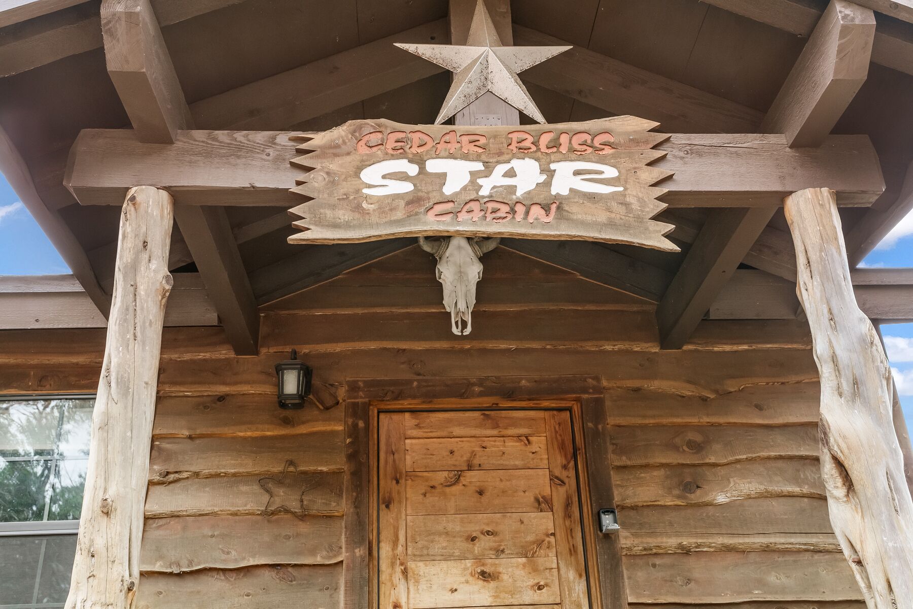 A wooden cabin entrance with a sign reading "Cedar Bliss Star Cabin."