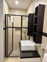 Une salle de bain moderne avec une douche à parois de verre, un lavabo blanc et un meuble en bois foncé.