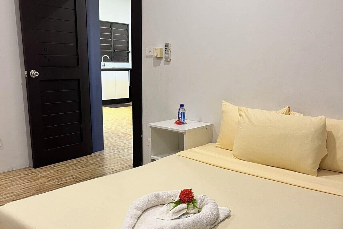 A hotel room with a bed, a bedside table, a water bottle, and a door leading to a balcony.