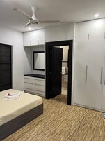 Une chambre à coucher avec un lit, une armoire, un miroir et un ventilateur de plafond.