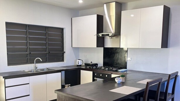 Una cucina moderna con isola centrale, mobili bianchi e piano di lavoro nero.