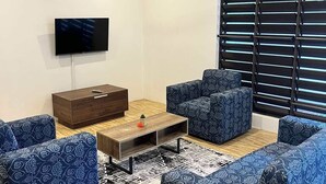 Un soggiorno moderno con televisione a schermo piatto, ventola a soffitto e un'ampia finestra con tende.