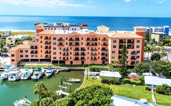 A multi-story hotel with balconies, a marina with boats, and a view of the ocean.