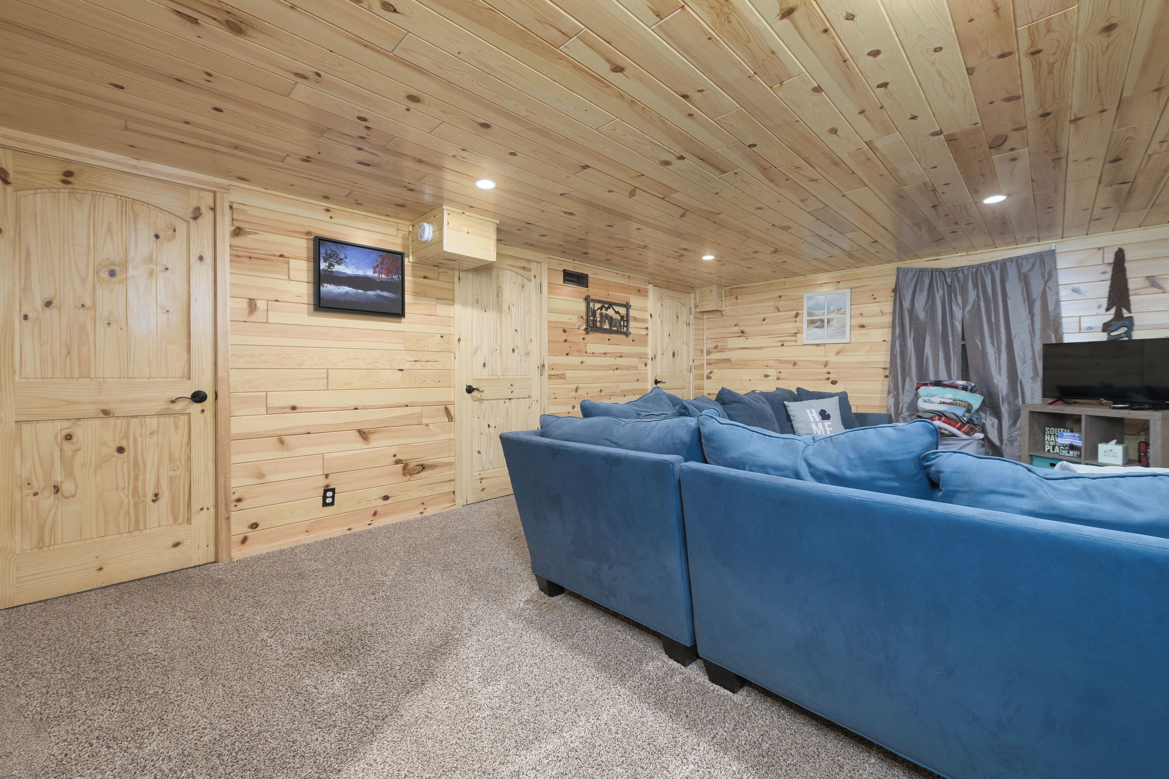 A log cabin interior with a blue sofa, wooden walls, and a television.