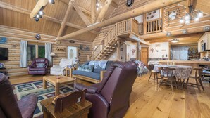 A log cabin interior with a living room, dining area, and kitchen.