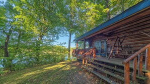 A rustic cabin with a wooden deck and stairs leading to a porch.