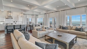 Un salón amplio con un sofá grande, una mesa de centro y un comedor con una cocina al fondo.