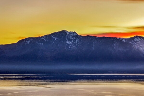 A mountain range with a clear sky and calm water in the foreground.