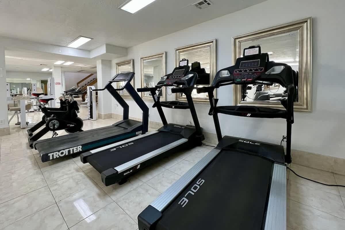 A gym with treadmills, stationary bikes, and a weight machine.