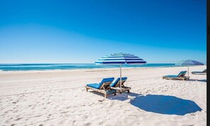 A beach with sun loungers and striped umbrellas. - Summer House 204A | Oceanfront | Pools, Hot Tub, Tennis | My Beach Getaways (Orange Beach)
