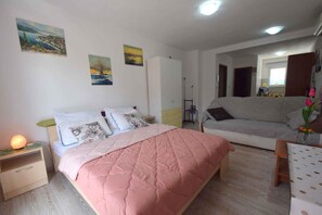 A bedroom with a bed, bedside tables, a dresser, and a sofa. - Studio with air conditioning (Rasopasno)