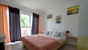 Une chambre à coucher avec un lit, des rideaux, une chaise et des œuvres d’art accrochées au mur.