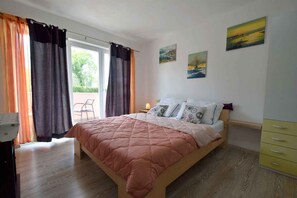 A bedroom with a bed, curtains, a chair, and artwork on the wall.