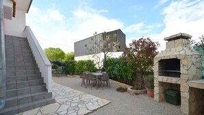 Une terrasse dotée d’une cheminée en pierre, de sièges extérieurs et d’un escalier menant à un bâtiment.