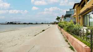 A beachside walkway with a clear view of the sea, a building with large windows, and a palm tree. - San Diego Home w/ Deck: Walk to Mission Beach! (San Diego)