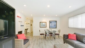 A modern living room with a flat-screen TV, a fireplace, a dining area with a table and chairs, and a leather sofa. - San Diego Home w/ Deck: Walk to Mission Beach! (San Diego)