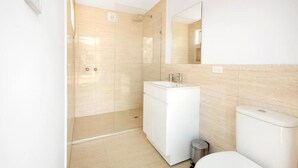 A modern bathroom with a glass-enclosed shower, a white sink, and a toilet. - Deluxe Leaf Bell Tent (Clydesdale)