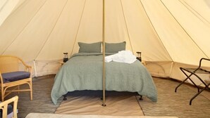 A tent with a bed, a chair, and a small table. - Deluxe Leaf Bell Tent (Clydesdale)