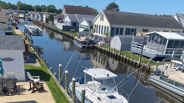 Een jachthaven met boten die aan een smalle waterweg liggen, omringd door woonhuizen en een klein bootje met een afdak.
