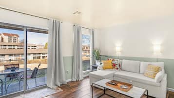 Un salón con sofá, mesa de centro y vistas a un patio interior a través de amplios ventanales.