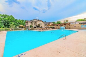 A swimming pool with a 4 FT depth marker, surrounded by a building with a covered patio area. - One Bedroom Serenity on the 17th | Amenities Golf (Branson)