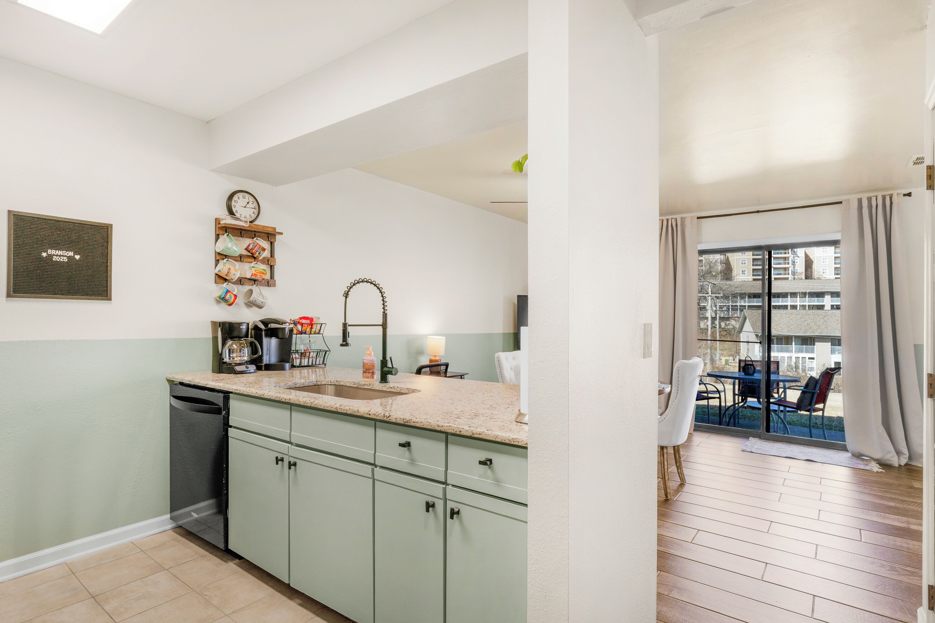 A modern kitchen with a sink, cabinets, and a clock on the wall.