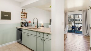 A modern kitchen with a sink, cabinets, and a clock on the wall.