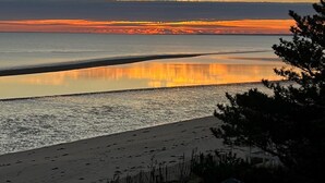 Una playa con un mar tranquilo, una cerca de madera y una pequeña construcción en primer plano.
