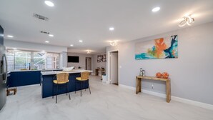 A modern kitchen with a central island, a dining area with chairs, and a large window. - MODERN HOME WITH HEATED POOL! CLOSE TO SAWGRASS MILLS MALL! FLEXIBLE CHECK IN 
  (Sunrise)
