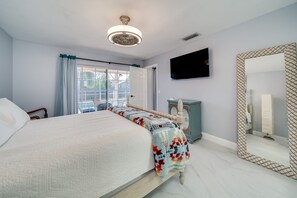 A bedroom with a large bed, a television mounted on the wall, and a decorative mirror. - MODERN HOME WITH HEATED POOL! CLOSE TO SAWGRASS MILLS MALL! FLEXIBLE CHECK IN 
  (Sunrise)