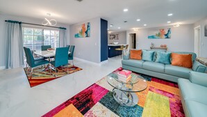 A modern living room with a sofa, coffee table, and dining area. - MODERN HOME WITH HEATED POOL! CLOSE TO SAWGRASS MILLS MALL! FLEXIBLE CHECK IN 
  (Sunrise)