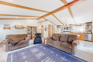 Relax in a spacious living area with high ceilings, two sofas, a leather armchair, and a bookshelf.