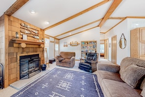 Cozy living room with a fireplace, comfortable seating, and a bookshelf filled with books.