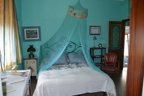 A bedroom with a bed under a canopy, a nightstand with a lamp, a chair, and a framed picture on the wall. - la castellana una finestra sul mare (Lerici)