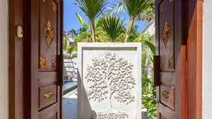 A wooden gate with intricate carvings leading to a pool area.