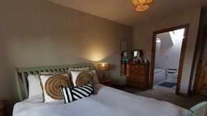 A bedroom with a bed, a dresser, a mirror, and a door leading to a bathroom.
