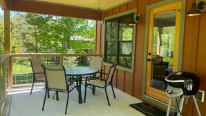 Une terrasse couverte avec une table et des chaises, un ventilateur de plafond et un barbecue.