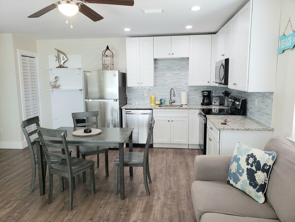A modern kitchen with white cabinets, stainless steel appliances, and a granite countertop.